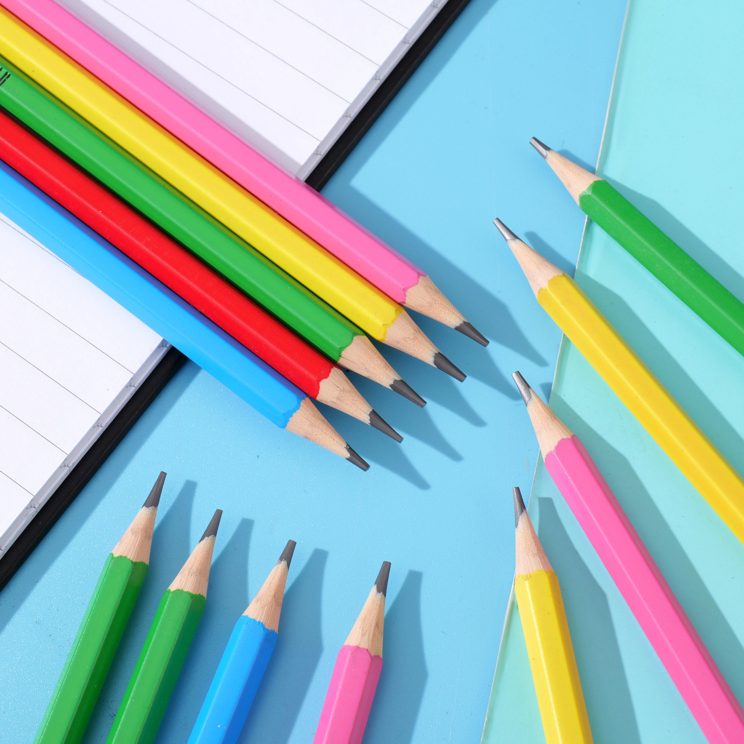Pencils of various colors placed on a blue paper, children's learning stationery